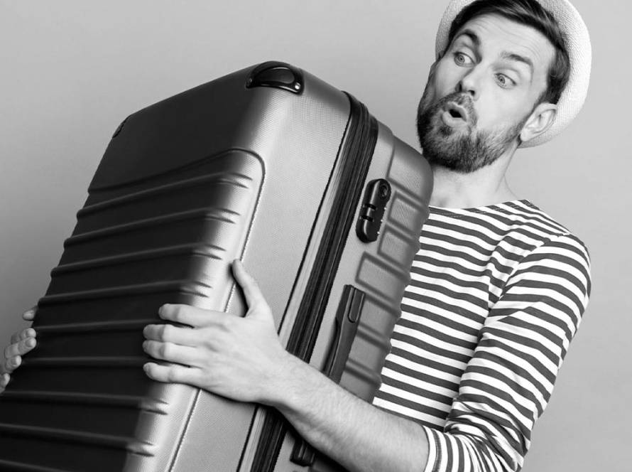 Joven sosteniendo una maleta grande con esfuerzo, ilustrando las soluciones de almacenamiento de equipaje para maletas voluminosas de Lock & Relax en Málaga.