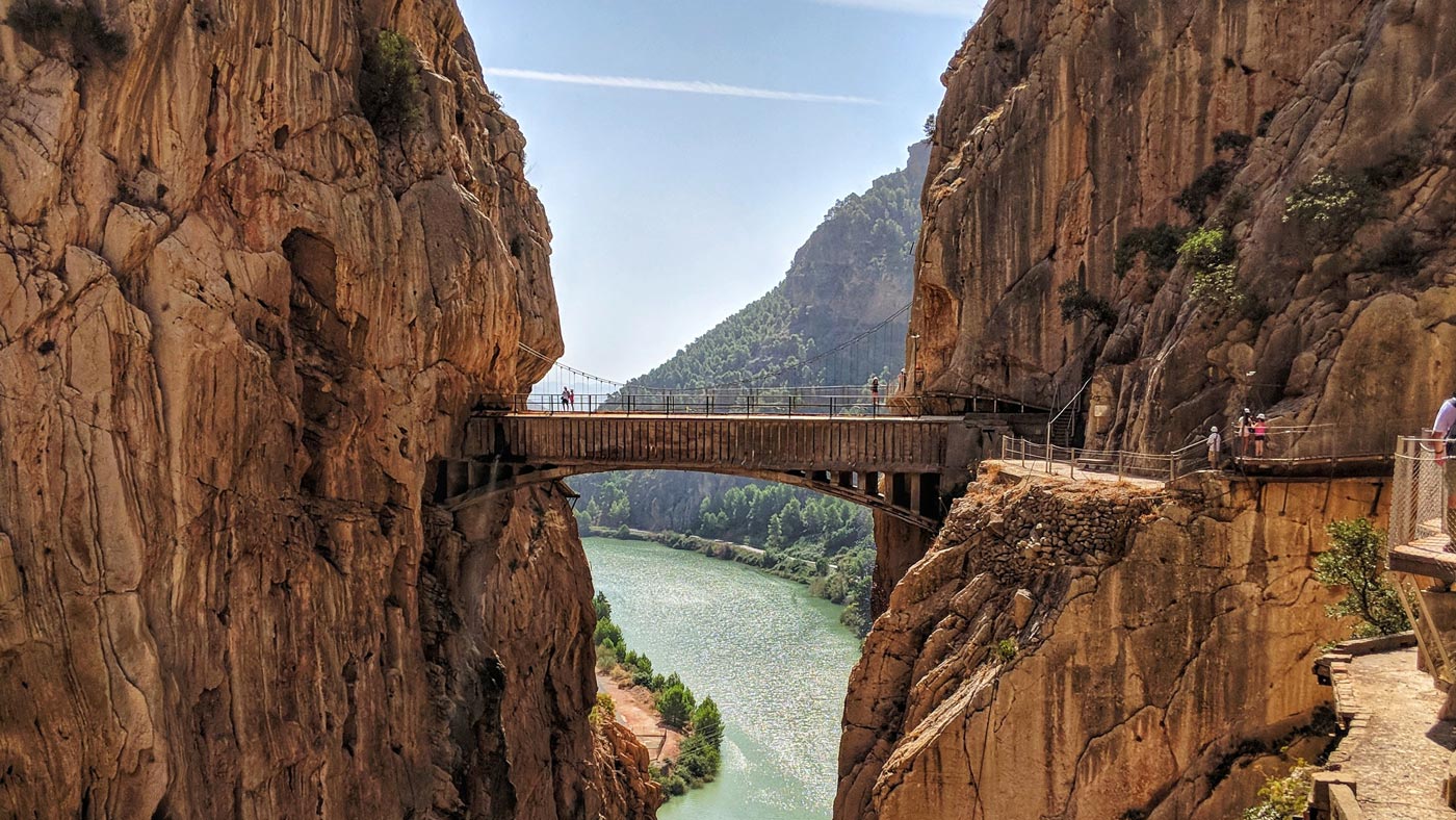 Cautivadora vista de los vertiginosos caminos del Caminito del Rey, en el interior de Málaga. Observamos un pequeño puente colgante peatonal que une dos impresionantes montañas. Excursiones Lock and Relax.